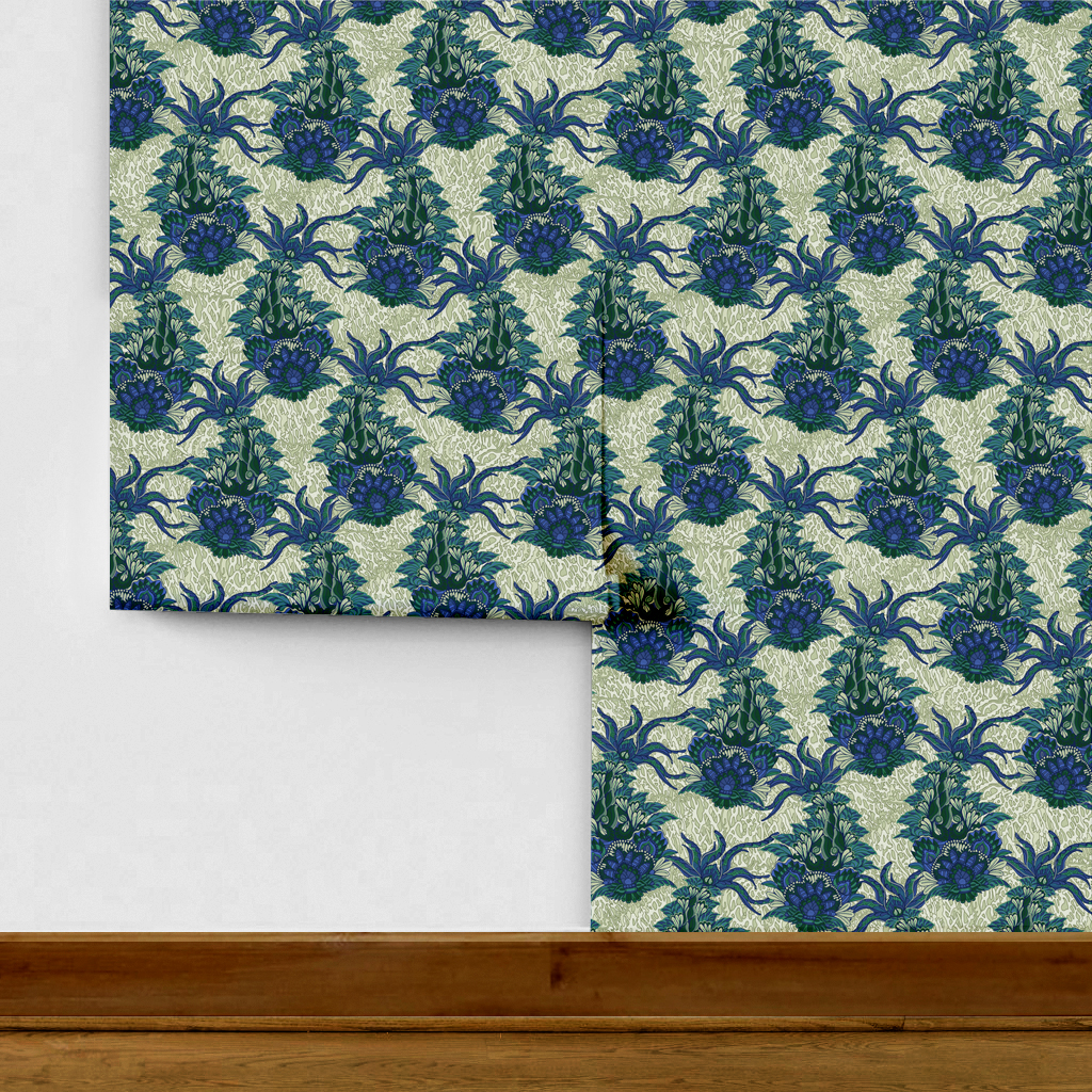 The artwork is a textile design featuring an intricate floral pattern. It showcases large, stylized flowers primarily in shades of blue and green. The flowers have detailed petals with layered, petal-like shapes creating a sense of depth and richness. Interwoven with the flowers are long, curved leaves and stems, adding dynamic movement to the composition. The background consists of a muted, light beige area patterned with subtle, organic shapes that resemble small leaves or plant forms, providing texture without overwhelming the main floral elements.